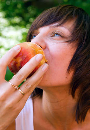 young beautiful woman enjoying tasty peachの写真素材