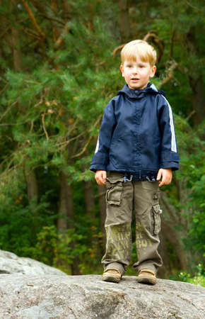 little boy standing on a stone in the forestの写真素材