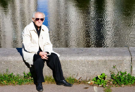 portrait of the old sad man sitting alone near the riverの写真素材