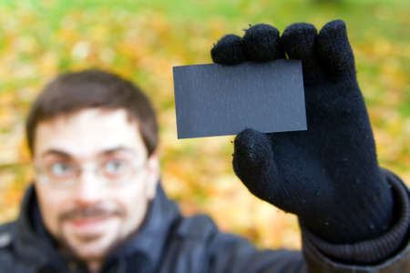 young man holding black business card and pointing it with his fingerの写真素材