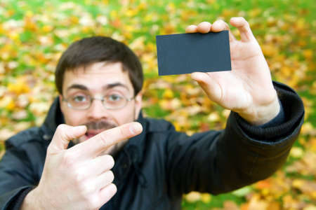 young man holding black business card and pointing it with his fingerの写真素材