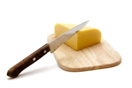 block of cheese on cutting board with a knife, slicing through it, isolated on white backgroundの写真素材