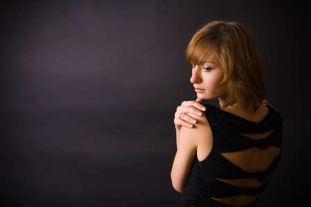 a black dressed woman with black background in the studio, is turning her backの写真素材