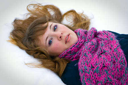 portrait of a beautiful young woman lying on a snowの写真素材