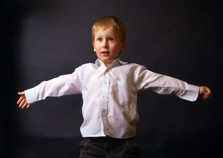 portrait of a little boy in studio, he is standing with open arms