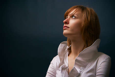 portrait of a young woman in white blouse in a studio, she is looking up