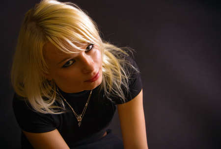 portrait of attractive blonde in a studio with black background, she is black dressed