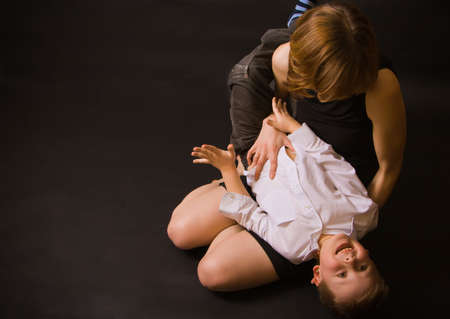portrait of a family - mother holding her little son and tickling him, he is laughing