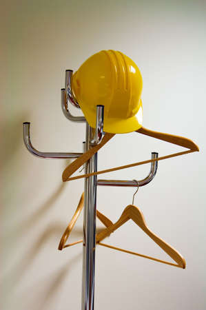 yellow hardhat is hanging on a coat rack with hangersの写真素材