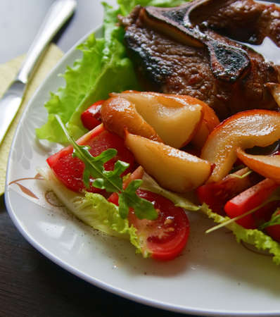 close-up grilled steak served with arugula, pear and tomatoの写真素材
