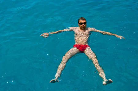 man in glasses for diving is swimming on the surface of blue seaの写真素材
