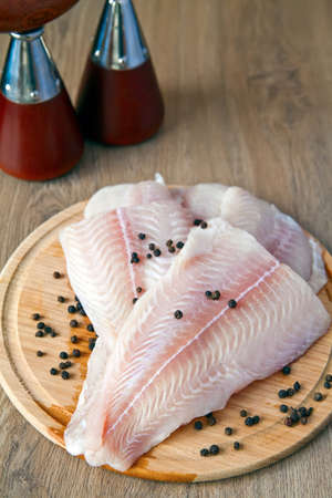raw fish pangasius with black pepper on a wood board