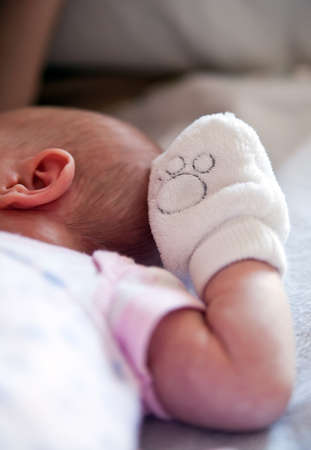 close-up newborn baby, focus on a mitten on her handの写真素材