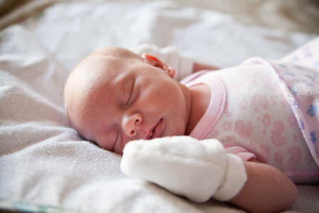 close-up little newborn girl sleeping in her bedの写真素材