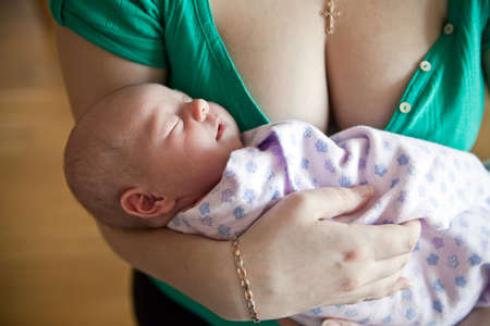 little newborn girl lying on her mother's hands, she is sleeping near her breastの写真素材