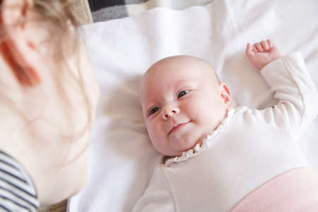 little smiling newborn girl looking on her mother