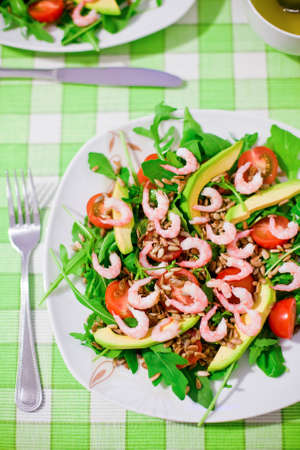 close-up fresh salad with shrimps, arugula, tomatoes, sunflower seeds and avocadoの写真素材