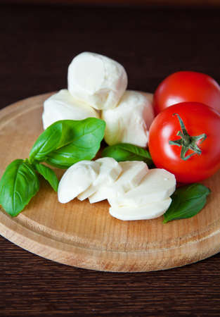 italian cheese mozzarella with tomato and basil on a cutting boardの写真素材