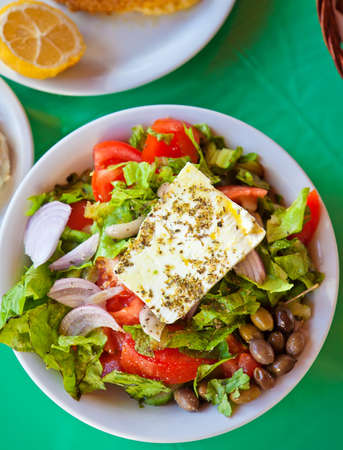 a plate with traditional greek salad with fresh vegetables, feta cheese and olivesの写真素材