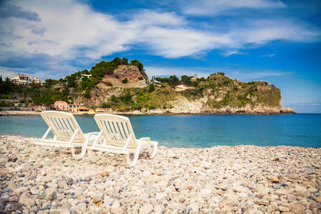chaise longues on a pebble beach at the seaの写真素材
