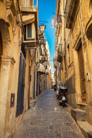narrow street of Syracuse with parked motorcyclesの写真素材