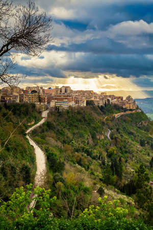 sun breaking through the clouds above the highest city in Sicily - Ennaの写真素材