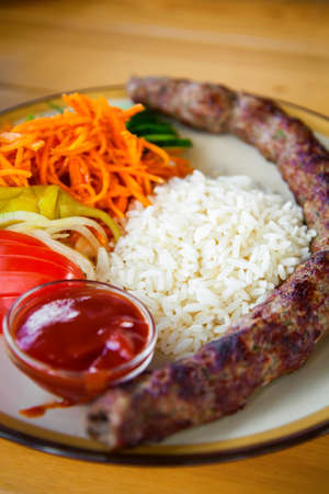 Traditional caucasian kebab - minced meat threaded on a skewer and roasted on the grill. It is made mostly of minced lamb with onion. Served with rice and vegetables.の写真素材