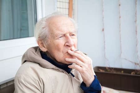 thoughtful old man smoking a cigaretteの写真素材