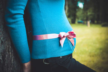 pregnant woman with a pink ribbon on her bellyの写真素材