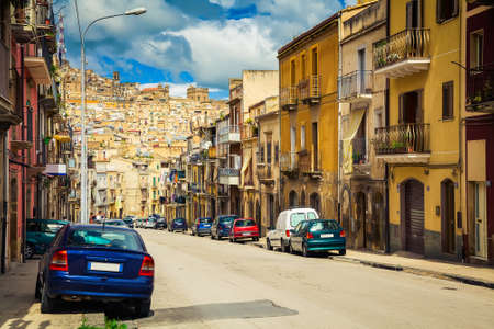 The street with old houses and cars in Caltagirone, Sicily, Italyの写真素材