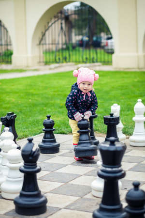 cute little girl playing with giant chess outdoorsの写真素材