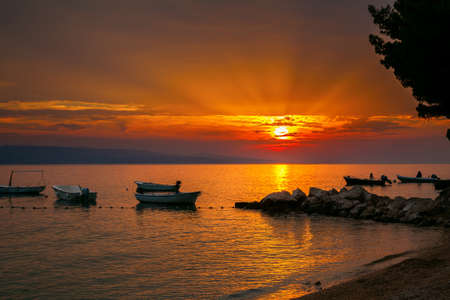 small boats with a sunset over the Adriatic sea on a background, Brela, Croatiaの写真素材