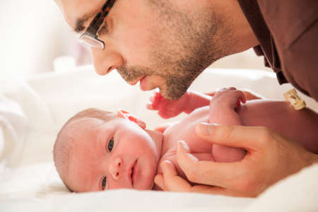 close-up portrait of a newborn baby and a father bent over herの写真素材