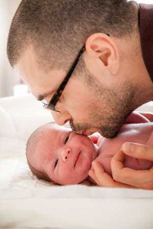 close-up portrait of father kissing his newborn babyの写真素材