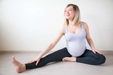 happy pregnant woman doing stretching exercises indoors