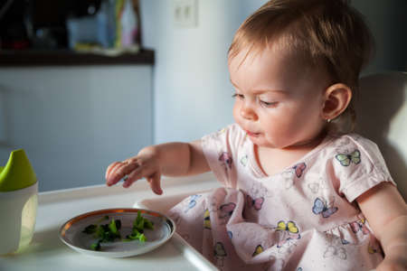 pretty little girl eating small pieces of broccoliの写真素材