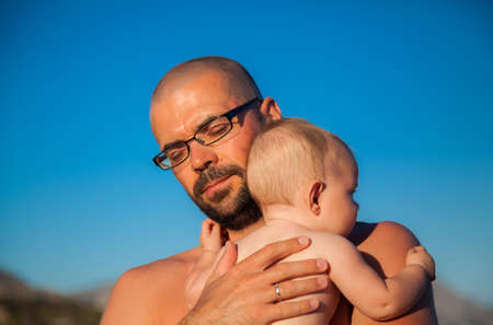 father with closed eyes hugging his newborn daughterの写真素材
