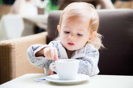 baby girl mixing sugar in a cup of teaの写真素材