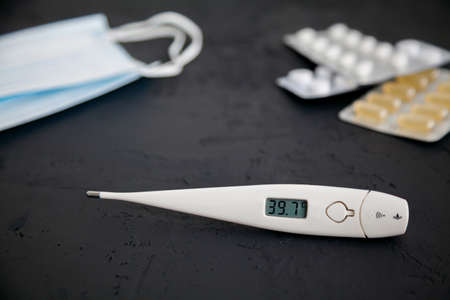 Thermometer 39.7, medicines and protective masks on a black background. Novel coronavirus 2019-nCoV, MERS-Cov middle East respiratory syndrome coronavirus. の写真素材