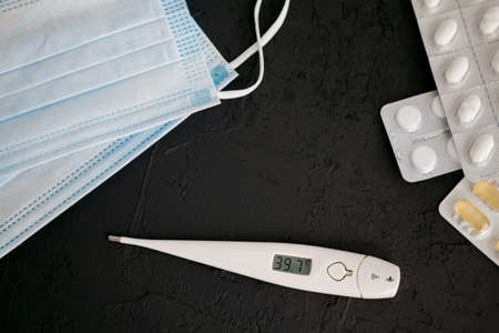 Thermometer 39.7, medicines and protective masks on a black background. Novel coronavirus 2019-nCoV, MERS-Cov middle East respiratory syndrome coronavirus. の写真素材