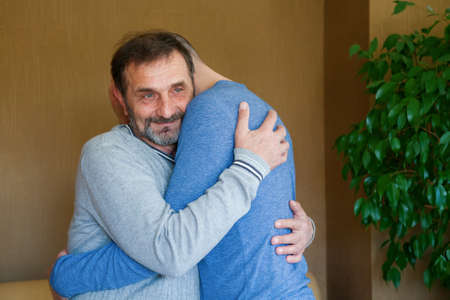 Pensive senior man hugging his adult son. Father's day concept.の写真素材