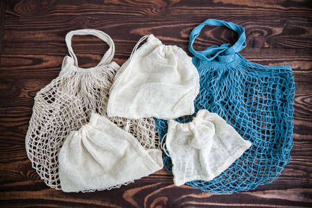 White and blue textile eco bags on wooden background. Eco friendly, reuse and zero waste concept.