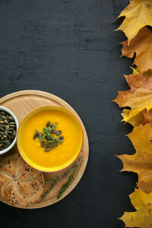 Homemade pumpkin cream soup with seeds and herbs on a black background. Top view, copy-space.の写真素材