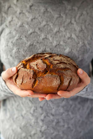 Woman's hands holding a beautiful homemade round rye bread