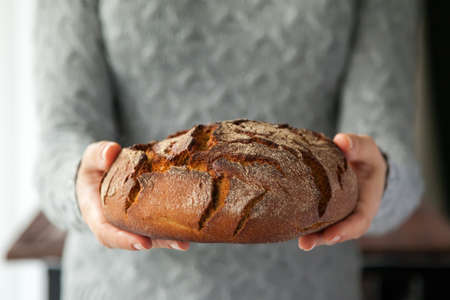 Woman's hands holding a beautiful round rye bread