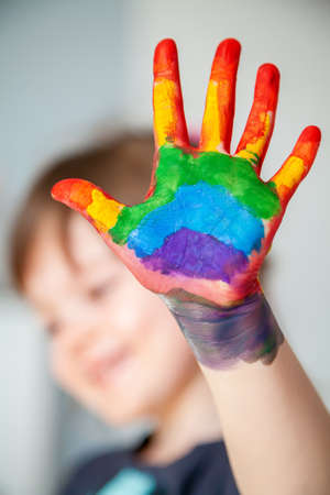 Cute little girl showing her hand with rainbow painted on her palmの写真素材