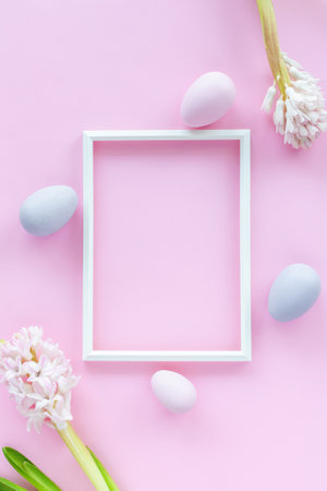 Minimalistic Easter holiday background with pastel colored eggs, photo frame and hyacinth flowers on a pink background. Flat lay greeting card with space for text. Easter decoration, minimalist design, modern design template.の写真素材