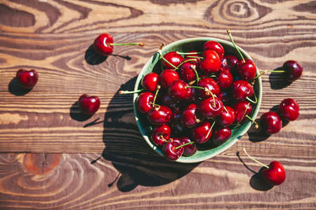 Flat lay fresh and ripe cherry in a bowl on a wooden backgroundの写真素材
