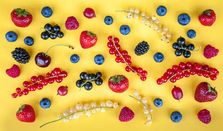 Various ripe fresh summer berries on a yellow backgroundの写真素材
