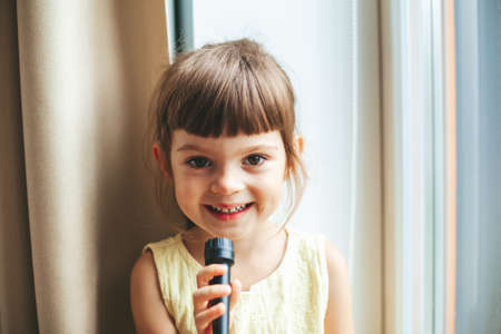 Cute smiling singing little girl with microphoneの写真素材